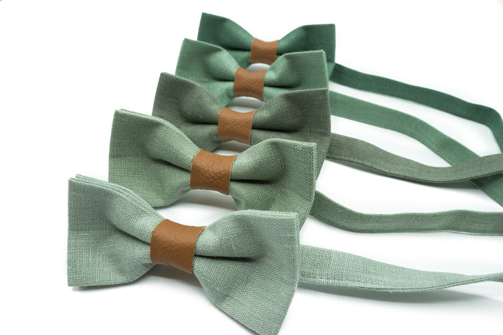 Close-up of a sage green bow tie with a tan leather center, elegant texture visible.