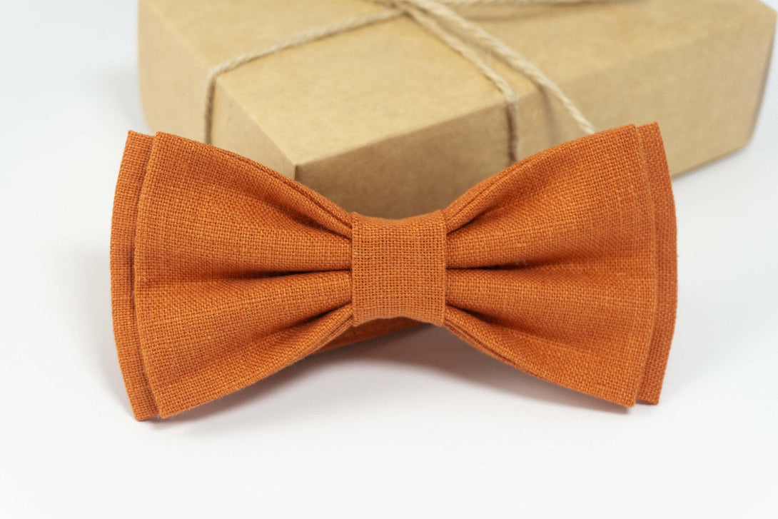 Close-up of a burnt orange linen bow tie, showcasing its textured fabric and elegantly tied shape, ideal for formal attire.