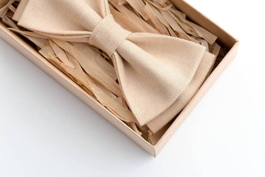 Beige linen bow tie in a rustic gift box with straw filling, perfect for weddings, grooms, and classic country-style events.